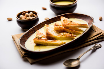 shahi tukra/tukda or Double ka meetha is a bread pudding Indian sweet of fried bread slices soaked in rabid or sweet saffron milk garnished with dry fruits, selective focus
