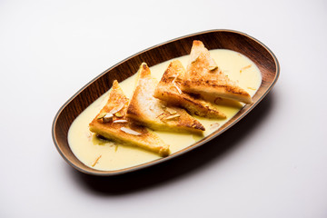 shahi tukra/tukda or Double ka meetha is a bread pudding Indian sweet of fried bread slices soaked in rabid or sweet saffron milk garnished with dry fruits, selective focus