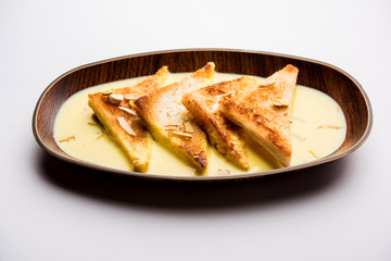 shahi tukra/tukda or Double ka meetha is a bread pudding Indian sweet of fried bread slices soaked in rabid or sweet saffron milk garnished with dry fruits, selective focus