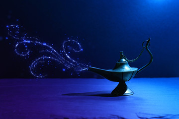 Image of magical mysterious aladdin lamp with glitter smoke. Dark background and dramatic light
