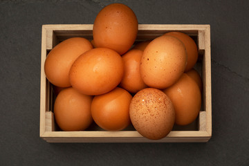 Brown Eggs in Small Wooden Crate From Above on a Gray Slate Plate