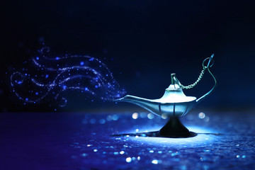 Image of magical mysterious aladdin lamp with glitter smoke. Dark background and dramatic light