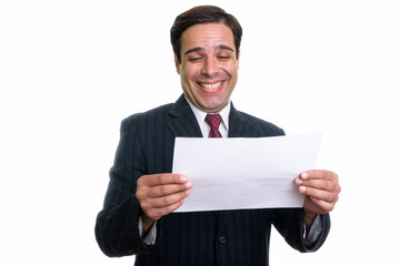 Studio shot of young happy Persian businessman smiling while rea