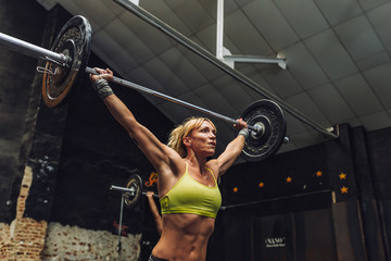 Blond woman lifting barbell in gym