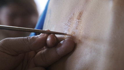 yantra tattoo or sak yant, thai sacred tattoo. master draws a girl colorless tattoo Sak Yant with a...