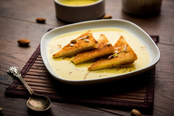 shahi tukra/tukda or Double ka meetha is a bread pudding Indian sweet of fried bread slices soaked in rabid or sweet saffron milk garnished with dry fruits, selective focus