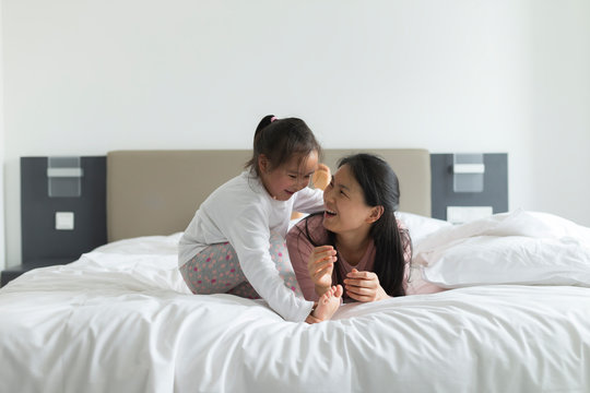 little girl playing with her mother in bed