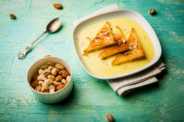 shahi tukra/tukda or Double ka meetha is a bread pudding Indian sweet of fried bread slices soaked in rabid or sweet saffron milk garnished with dry fruits, selective focus