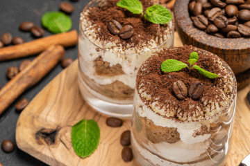 Classic tiramisu dessert in a glass on dark concrete background