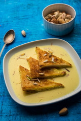 shahi tukra/tukda or Double ka meetha is a bread pudding Indian sweet of fried bread slices soaked in rabid or sweet saffron milk garnished with dry fruits, selective focus