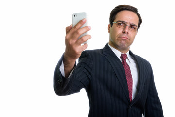 Studio shot of young Persian businessman taking selfie picture w