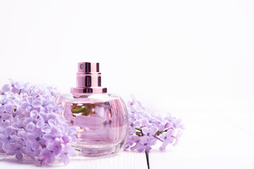 Obraz na płótnie Canvas pink bottle of women's perfume with lilac flowers on white wooden background