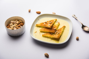 shahi tukra/tukda or Double ka meetha is a bread pudding Indian sweet of fried bread slices soaked in rabid or sweet saffron milk garnished with dry fruits, selective focus