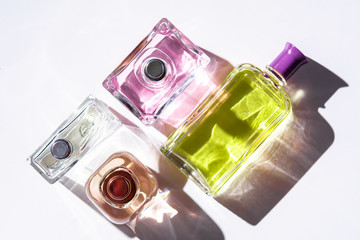 Unisex perfume bottles on white background with long hard shadows.