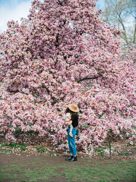 Mom holding toddler in front of blooming magnolia tree