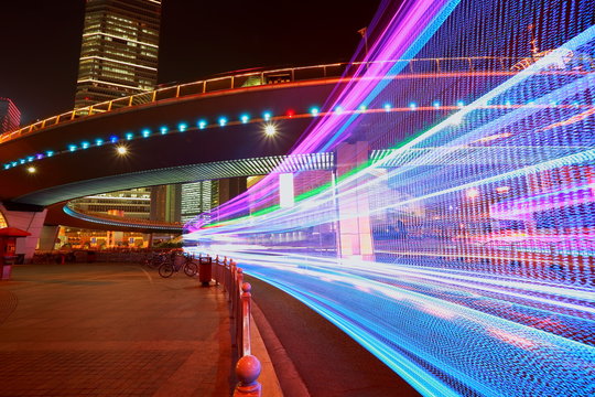The highway car rainbow light trails of modern city buildings