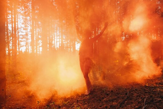 Silhouette of dancing woman in orange fog in sunset