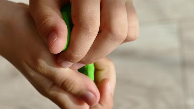 The child crumples in the hands of green clay. Children's games.
