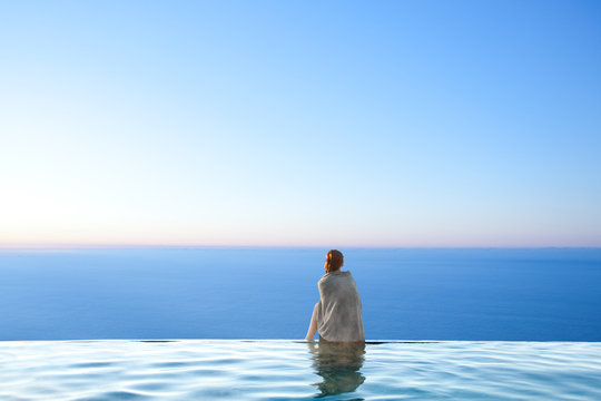 Woman sitting on edge of infinity pool
