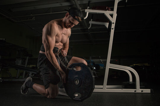 Man exercising with dipping belt and weight plate in gym