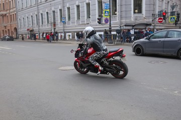 motorcyclist on a red motorcycle turning right on a city street