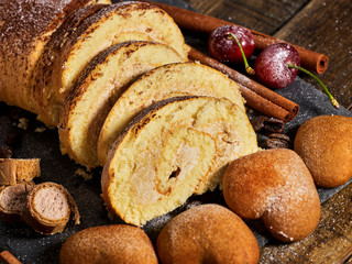 Sand cookies heart shape, rolled cake with cherry and cinnamon stick, coffee bean on kitchen on wooden table in village style. Perfect for breakfast.