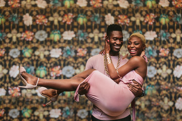 Smiling man carrying woman outdoors