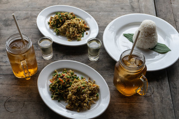 traditional Balinese food called lawar. Lawar is minced meat mixed with vegetables, long beans and spices then stirred evenly. Eat using rice and freash iced tea. Served on a wooden table