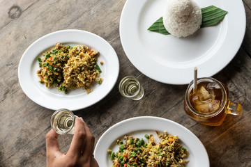 traditional Balinese food called lawar. Lawar is minced meat mixed with vegetables, long beans and spices then stirred evenly. Eat using rice and iced tea. Served on a wooden table with hand on it