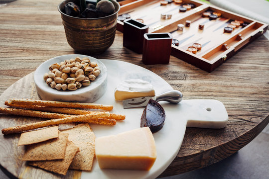 Wooden table with cheese platter and board game in backyard of new home