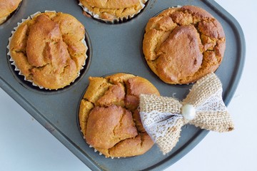 Tasty muffins on the baking sheet on the white table