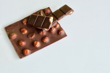 Tasty dark chocolate with hazelnuts on the white table
