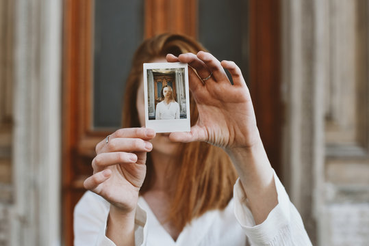 Woman holding instant photo in front of her face