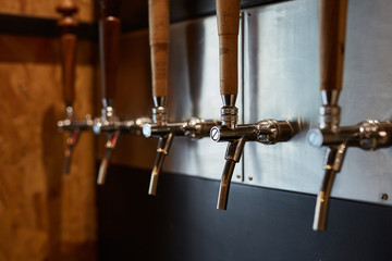 Multiple aligned draft beer taps in a bar