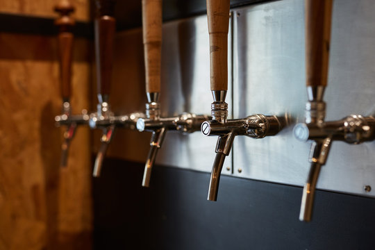 Multiple aligned draft beer taps in a bar