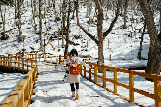 Traveler carrying a camera and backpack walking on a wooden trestle covered with snow, Sapporo, Hokkaido, Japan