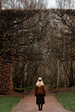 blode woman looking to a huge  dried bush in a garden