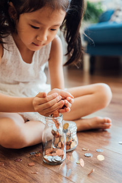 Adorable girl putting coins in jar