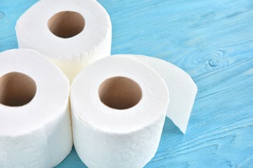 Rolls with white toilet paper with selective focus, top view. Toilet paper for daily personal hygiene on blue wooden background. Restroom recycle paper. Soft clean toilet paper. Roll of white towels 