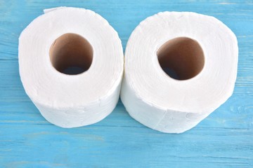 Rolls with white toilet paper with selective focus, top view. Toilet paper for daily personal hygiene on blue wooden background. Restroom recycle paper. Soft clean toilet paper. Roll of white towels 