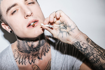 Fashionable tattooed guy with a modern haircut and a cigarette, attitude