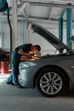 Technician investigating car engine with lamp