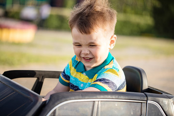 joy small boy is driving toy car on the playground  