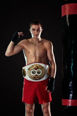 Sportsman, man boxer fighting in gloves with a championship belt. Isolated on black background with...