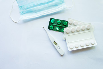 Medicaments on a white background, pills, thermometer, inhaler
