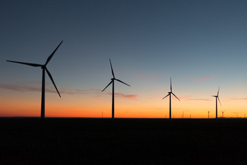 A landscape with windmills in a wind farm at sunset.