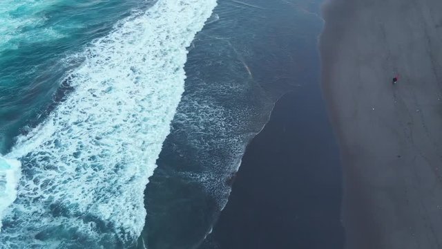 Aerial Drone tracking along beach people walking foot prints Azores Portugal