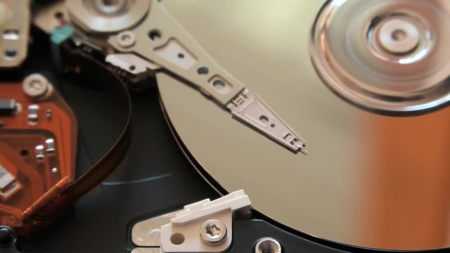 close up of interior of an hard disk drive writing data on the support with its head.