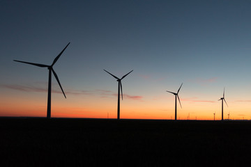 A landscape with windmills in a wind farm at sunset.