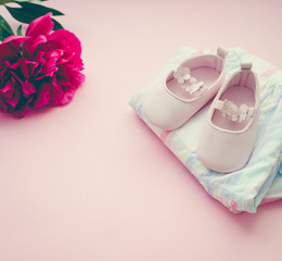 pink baby shoes and flowers on a pink background